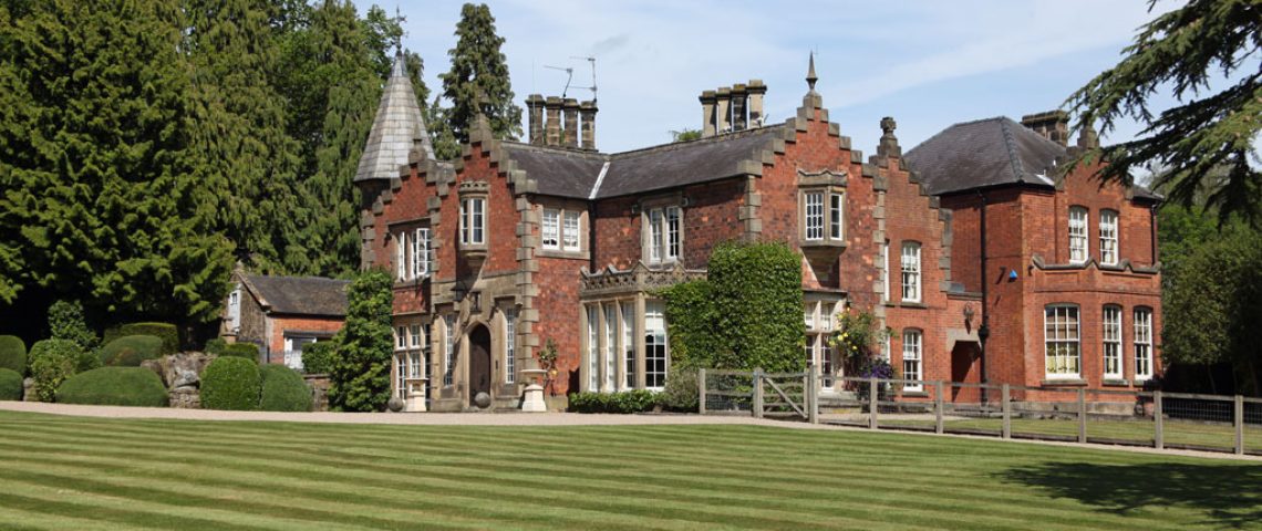 Gothic-style red brick country house with a striped lawn frontage