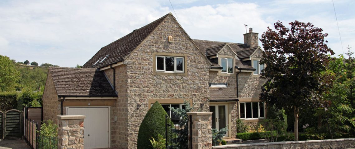 Stone-built detached family home with a gated driveway and garden
